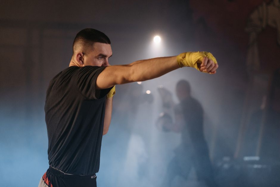 Boxer extending a straight punch in low-light training, showing the angle a body shot opens from