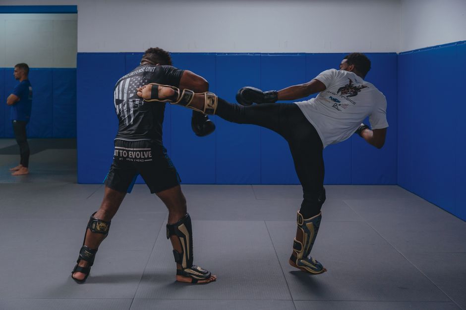 MMA fighters drilling kicks with shin pads in training