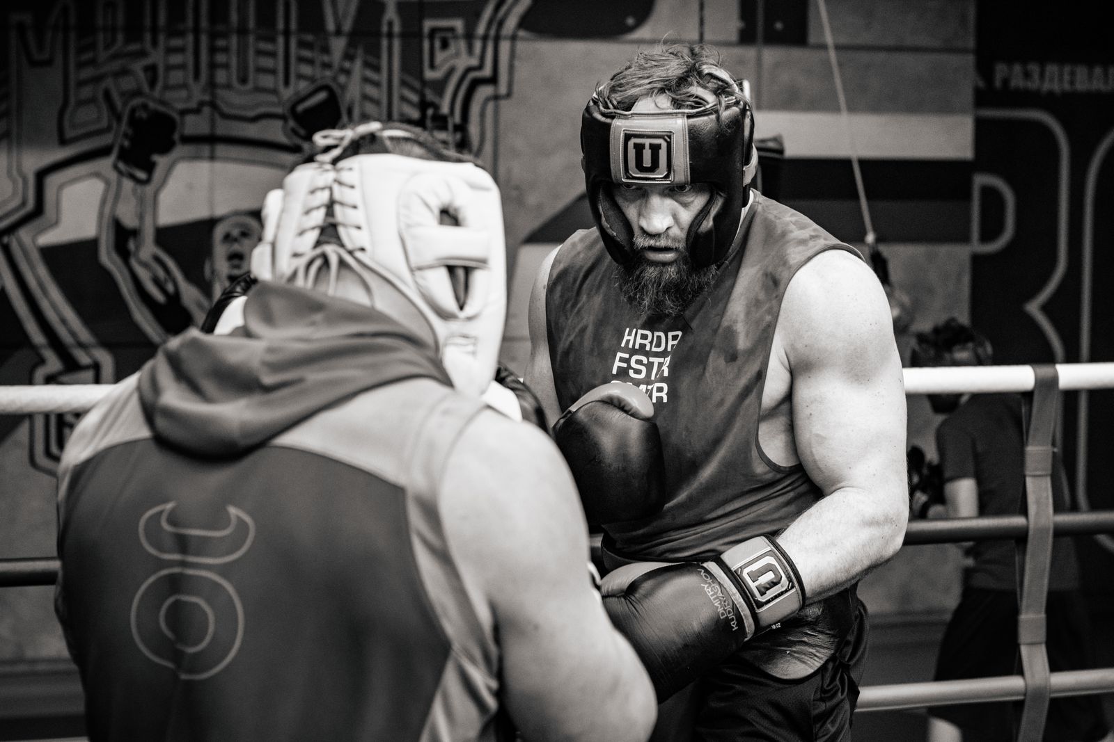 Two fighters sparring with headgear and gloves in a training gym setting