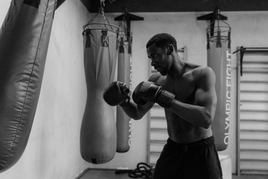 Boxer in stance with gloves up training in a gym, illustrating body-punching posture