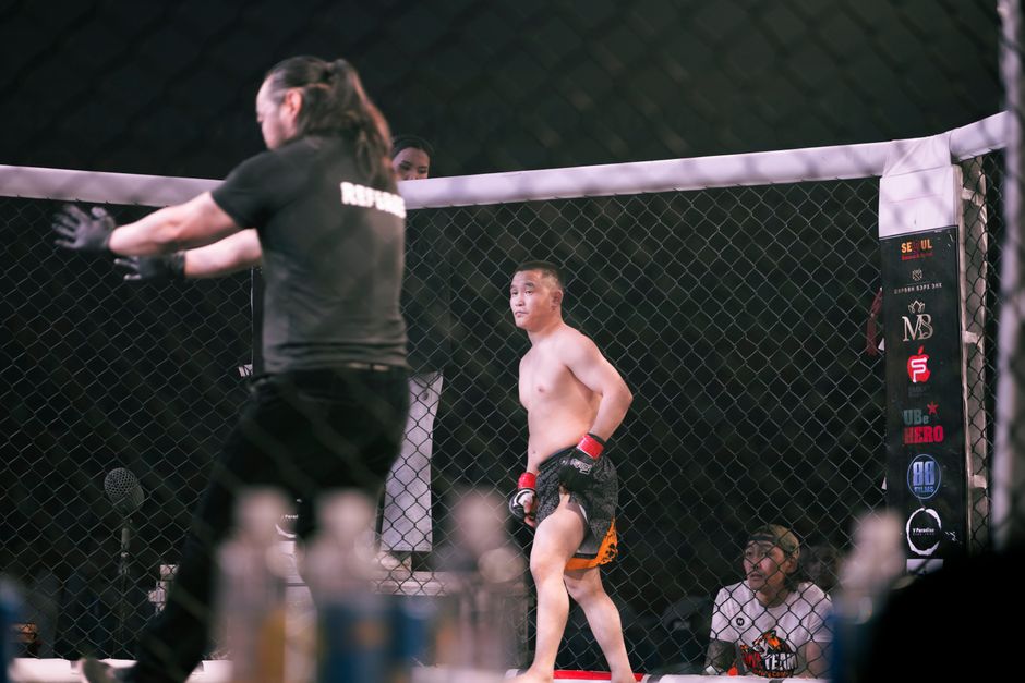 MMA fighter inside the cage with referee directing the action
