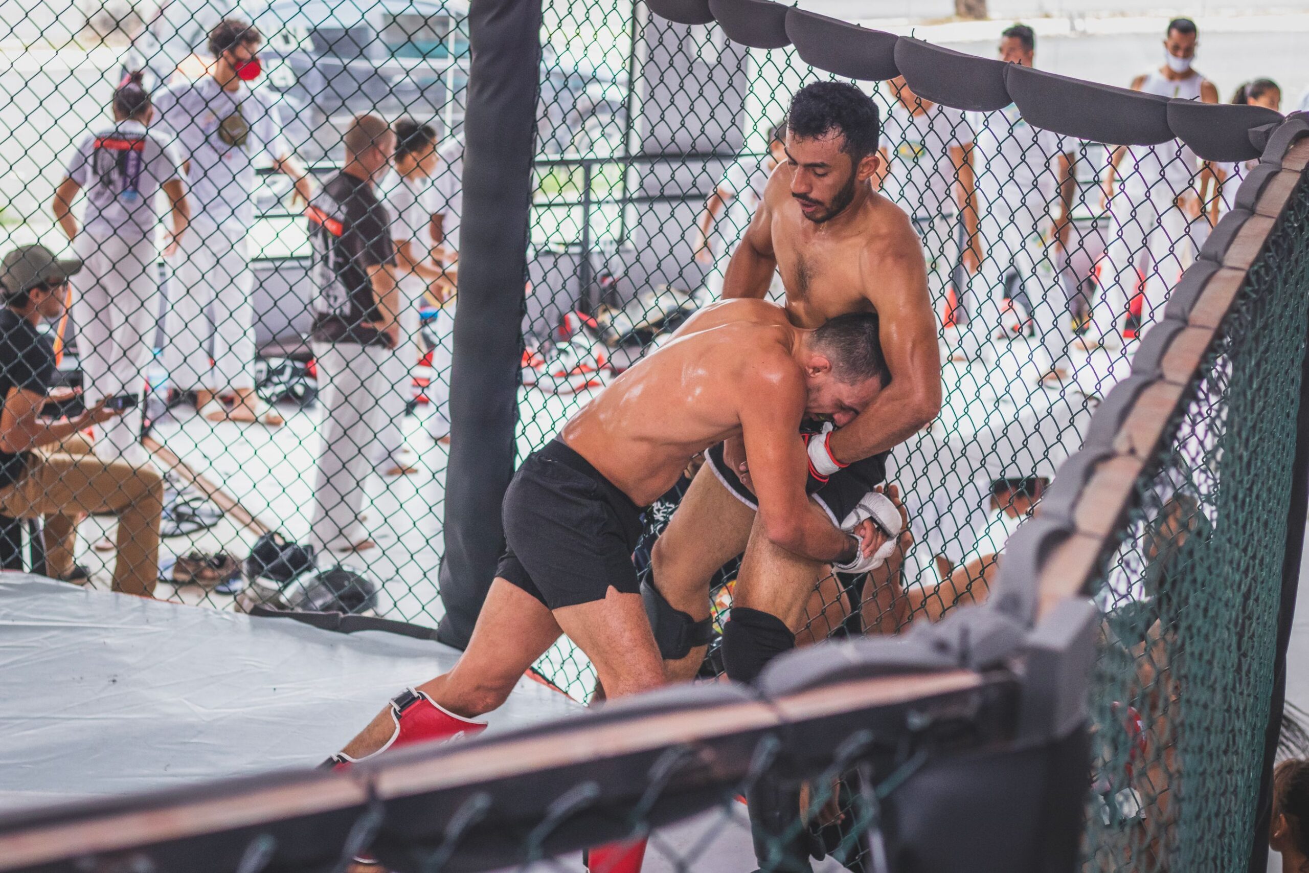 Two MMA fighters grappling in the cage during an intense exchange that taxes the aerobic system