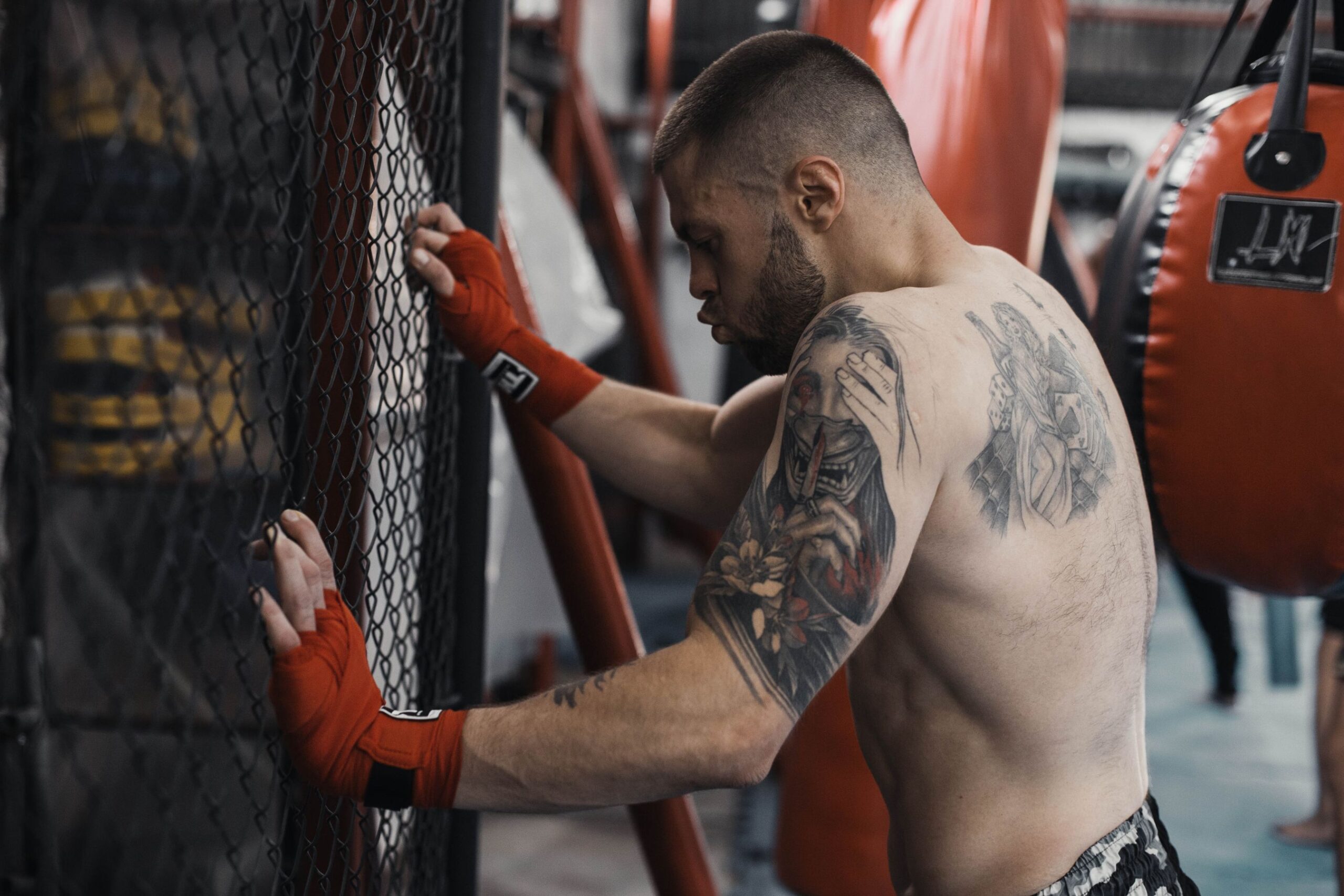 A tired MMA fighter leaning against the cage between rounds showing the cost of poor conditioning