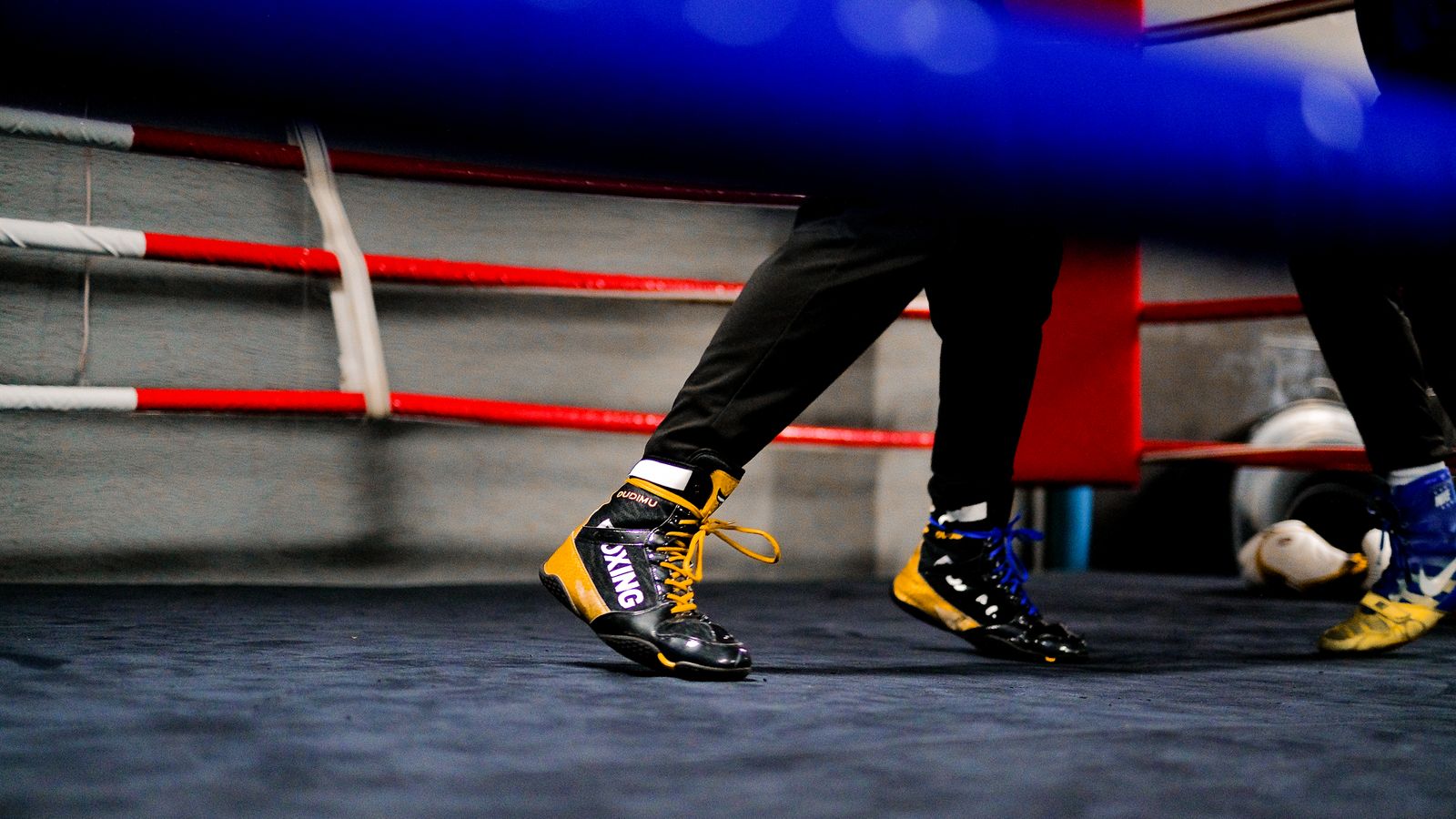 Close-up of a fighter's footwork in a training ring showing balanced stance and lead foot positioning