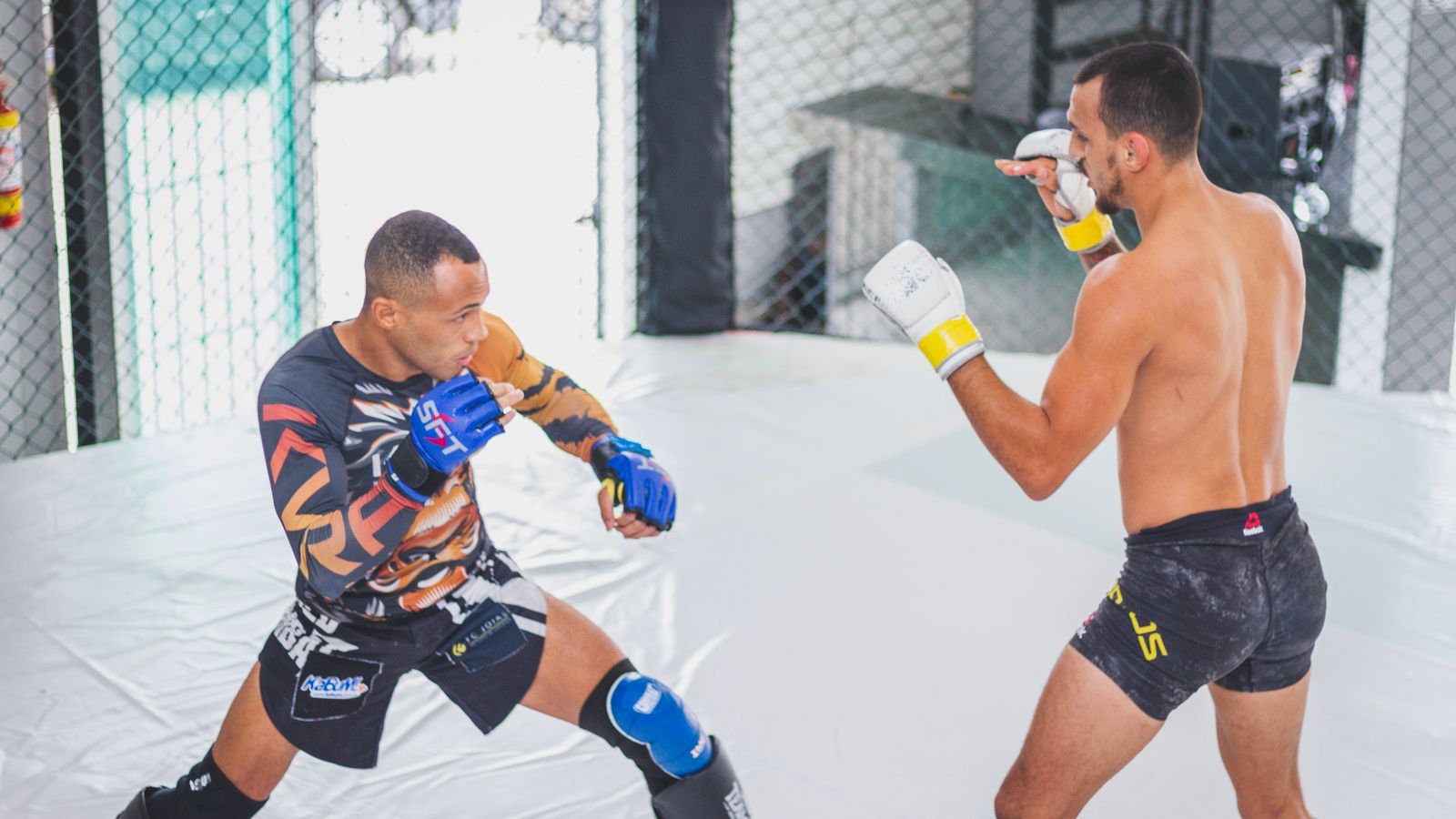 Two MMA fighters squared up in a cage demonstrating stance and footwork drilling