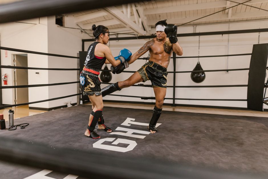 Muay Thai sparring with a high kick being thrown in a boxing ring
