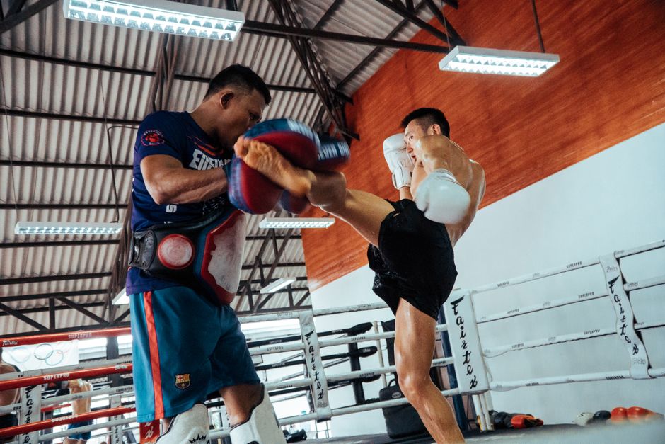 Fighter drilling kicks on pads in a Thailand Muay Thai gym
