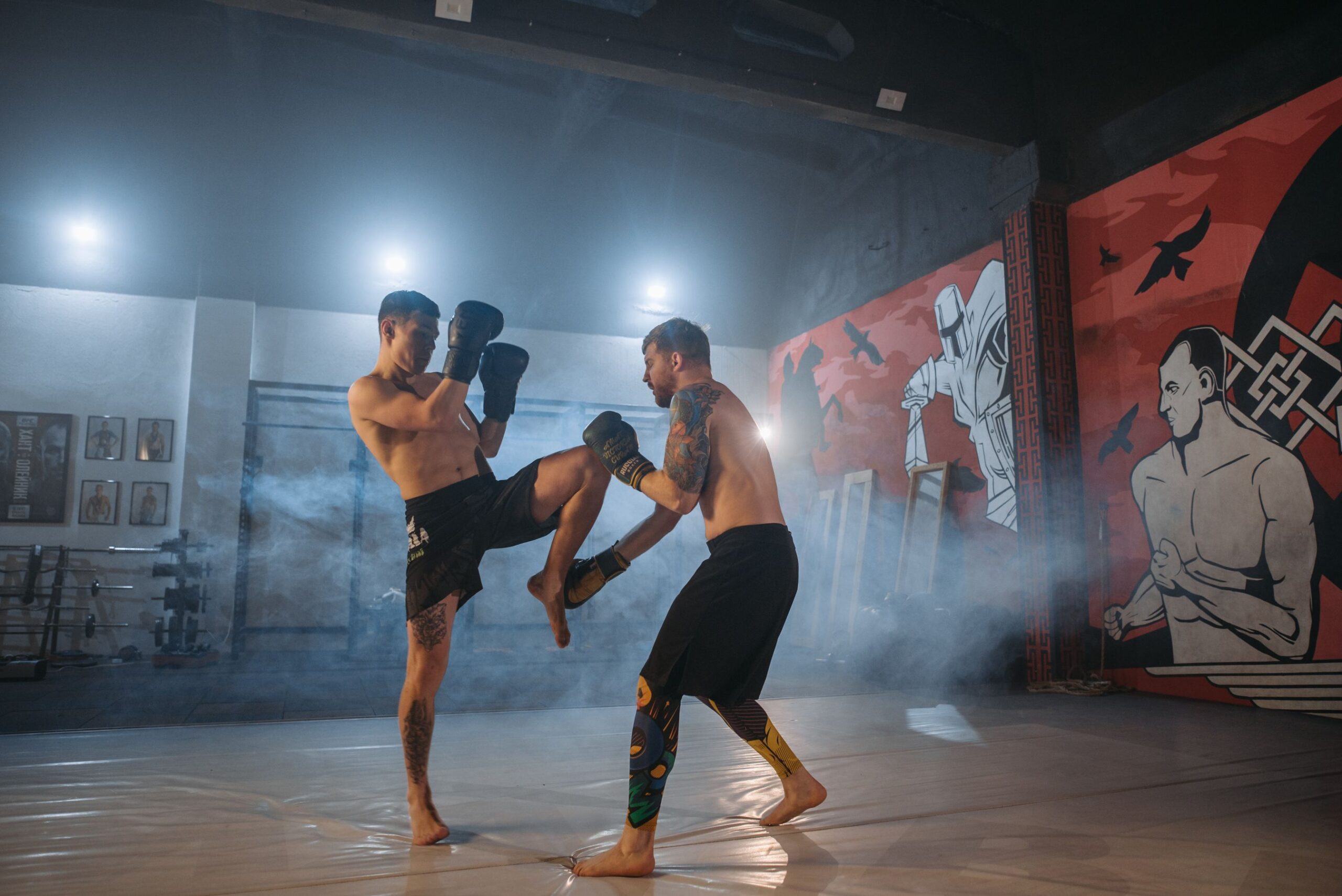 Two MMA fighters sparring with a kick exchange in a gym