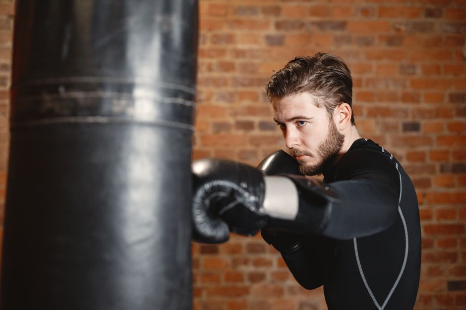 A boxer drilling punches on a heavy bag in a brick gym, representing fight-camp preparation