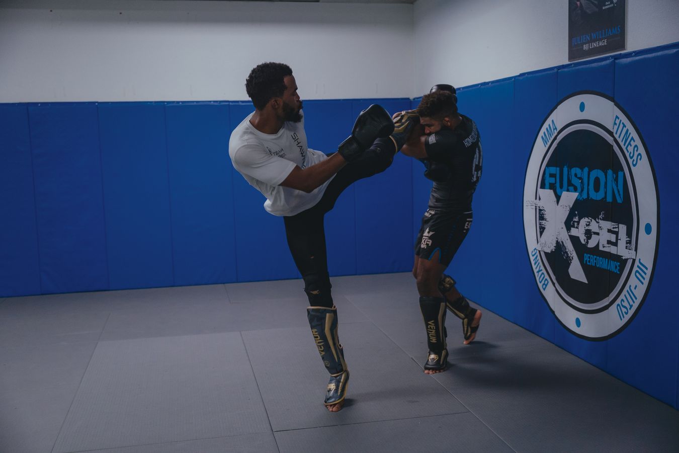 Two MMA fighters drilling a high kick defense in a gym