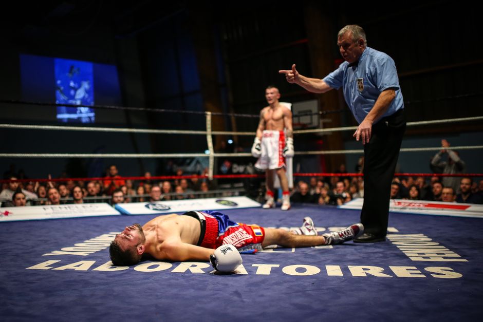 Boxer knocked out on the canvas as the referee waves off the fight