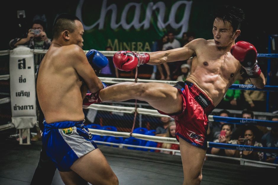 Muay Thai fighter landing a high kick during a stadium bout