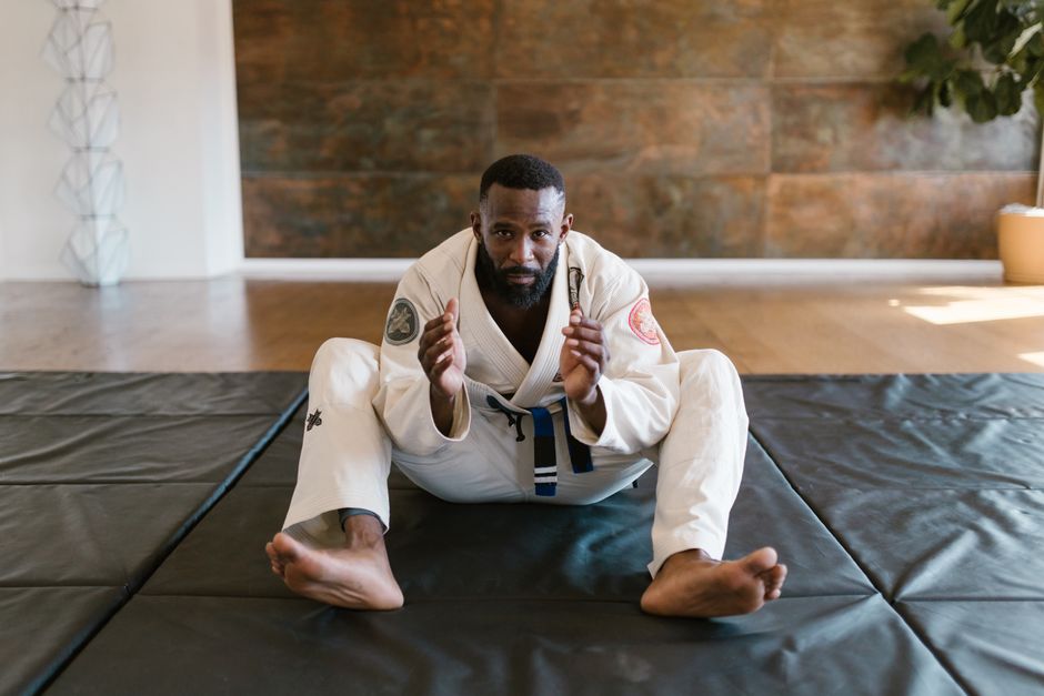 A jiu-jitsu practitioner in a white gi sitting on the mats