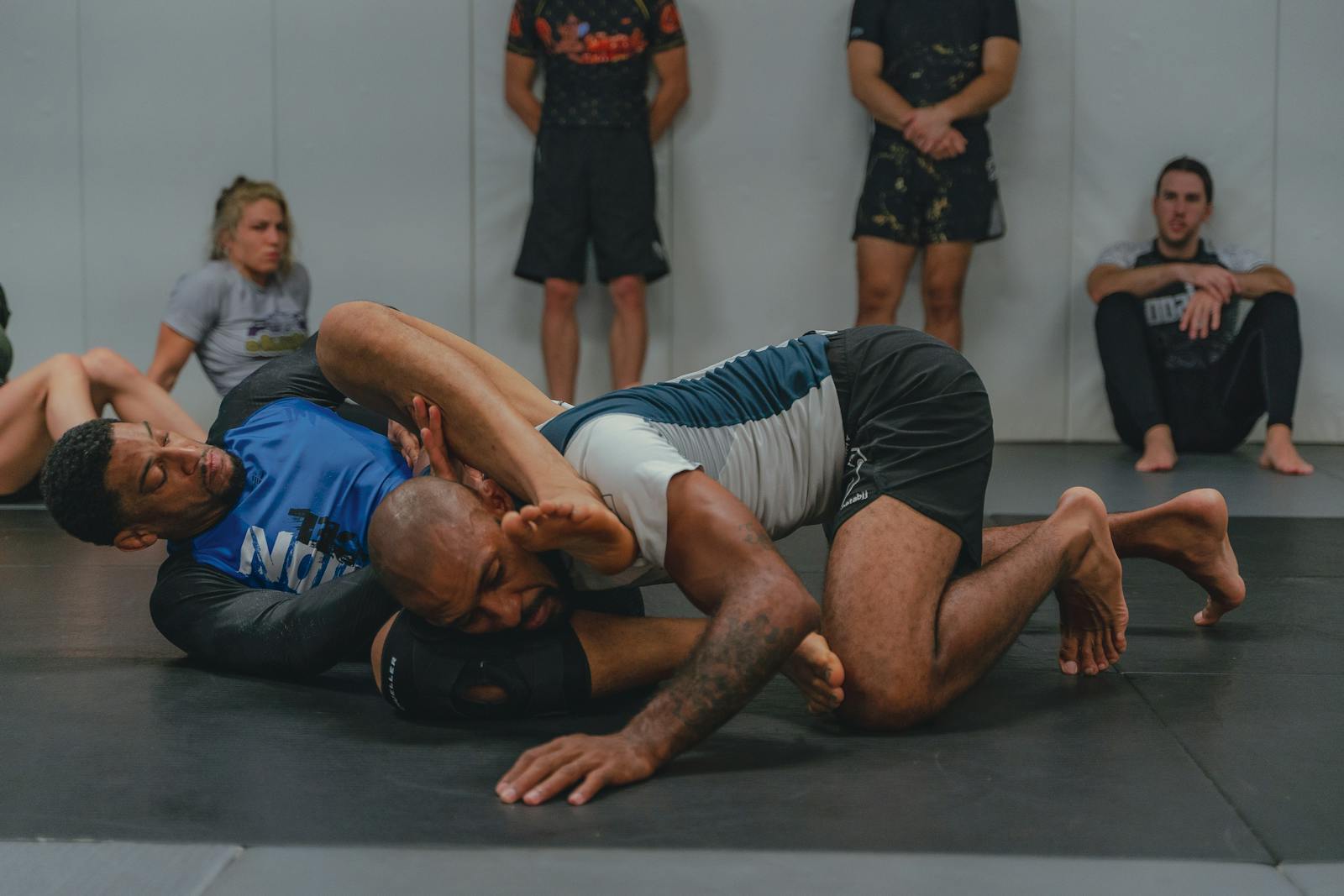 MMA fighters drilling grappling positions in a training room