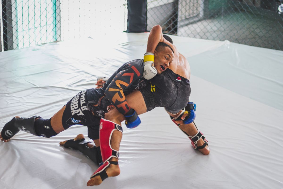 MMA fighters grappling inside the cage, showing wrestling and ground control