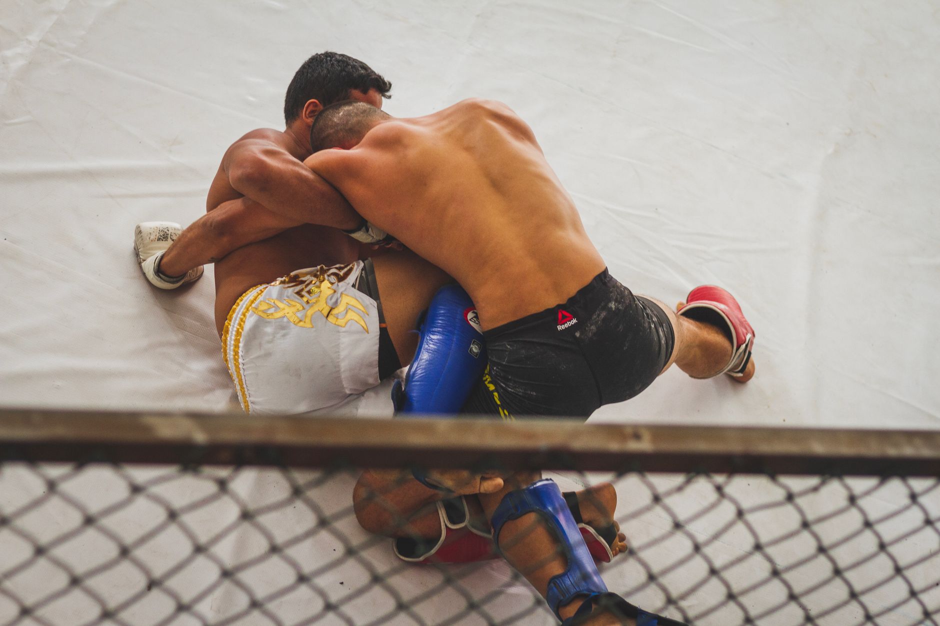 MMA fighters grappling on the mat with a front headlock guillotine control