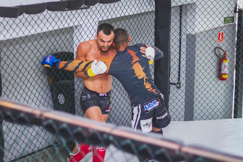 Two MMA fighters grappling in the cage