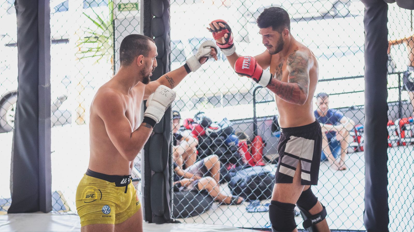 Two MMA fighters trading strikes in a cage, illustrating volume striking exchanges