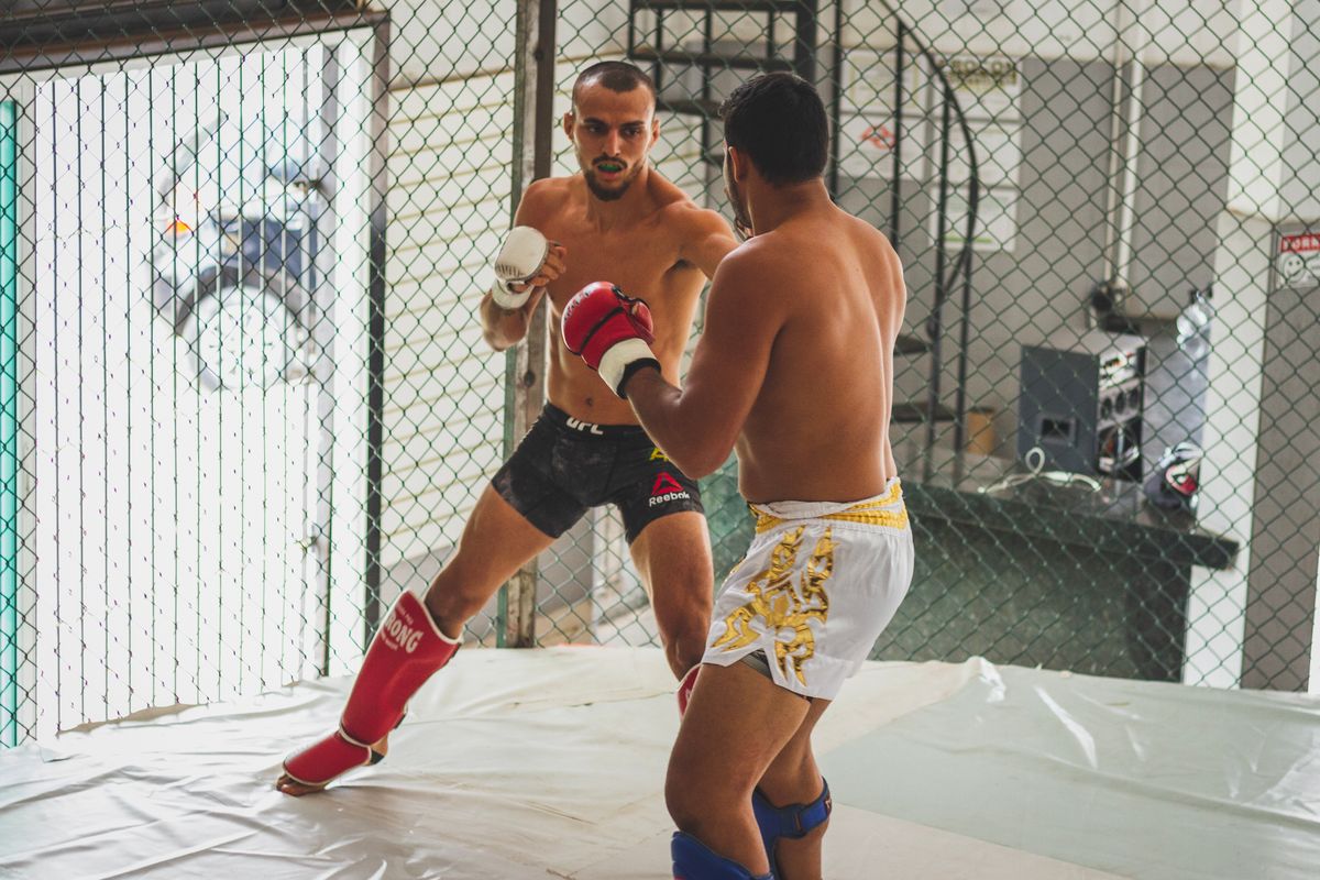Kickboxer managing distance against an opponent in a cage