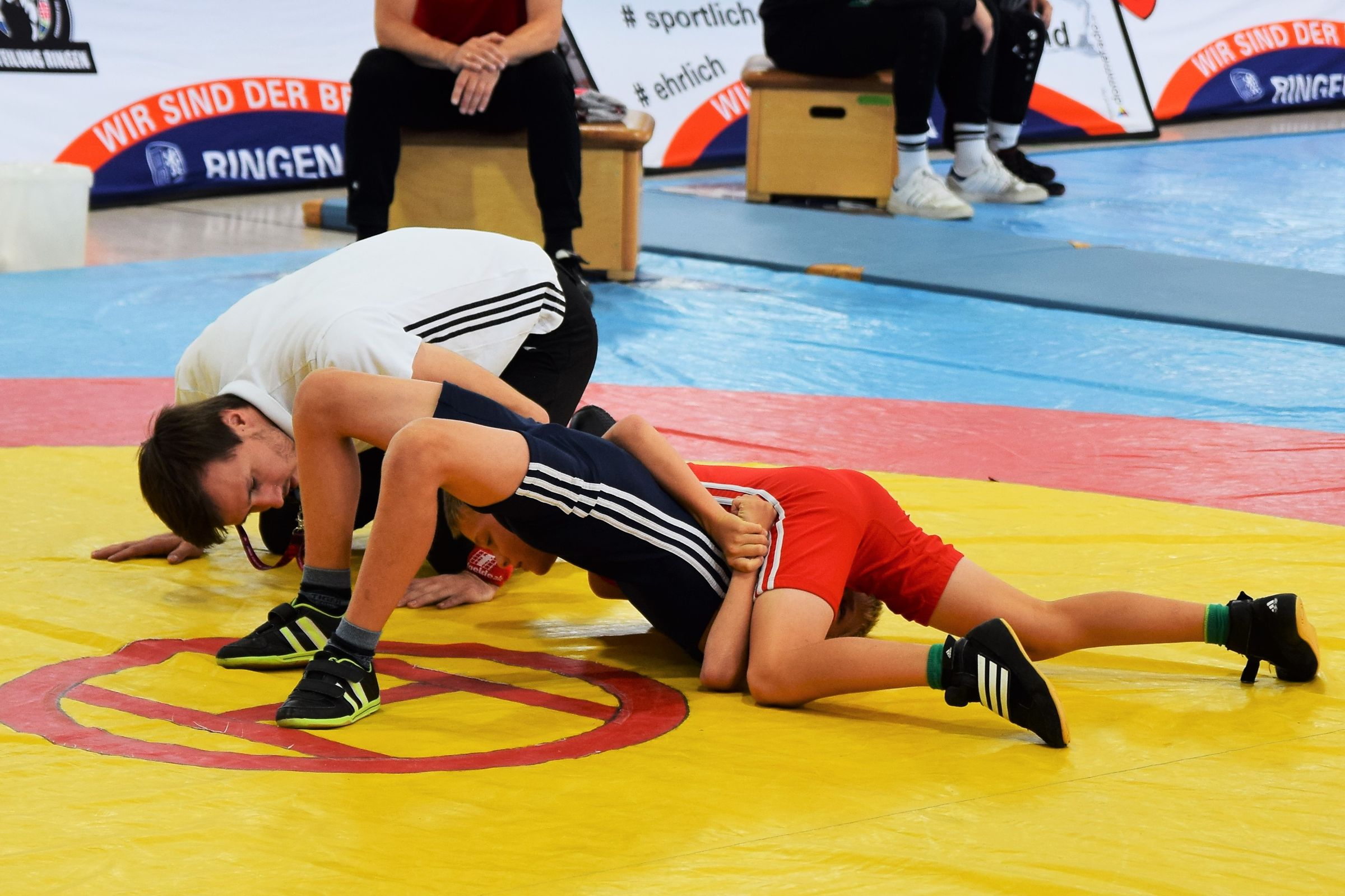 Two athletes grappling on a freestyle wrestling mat