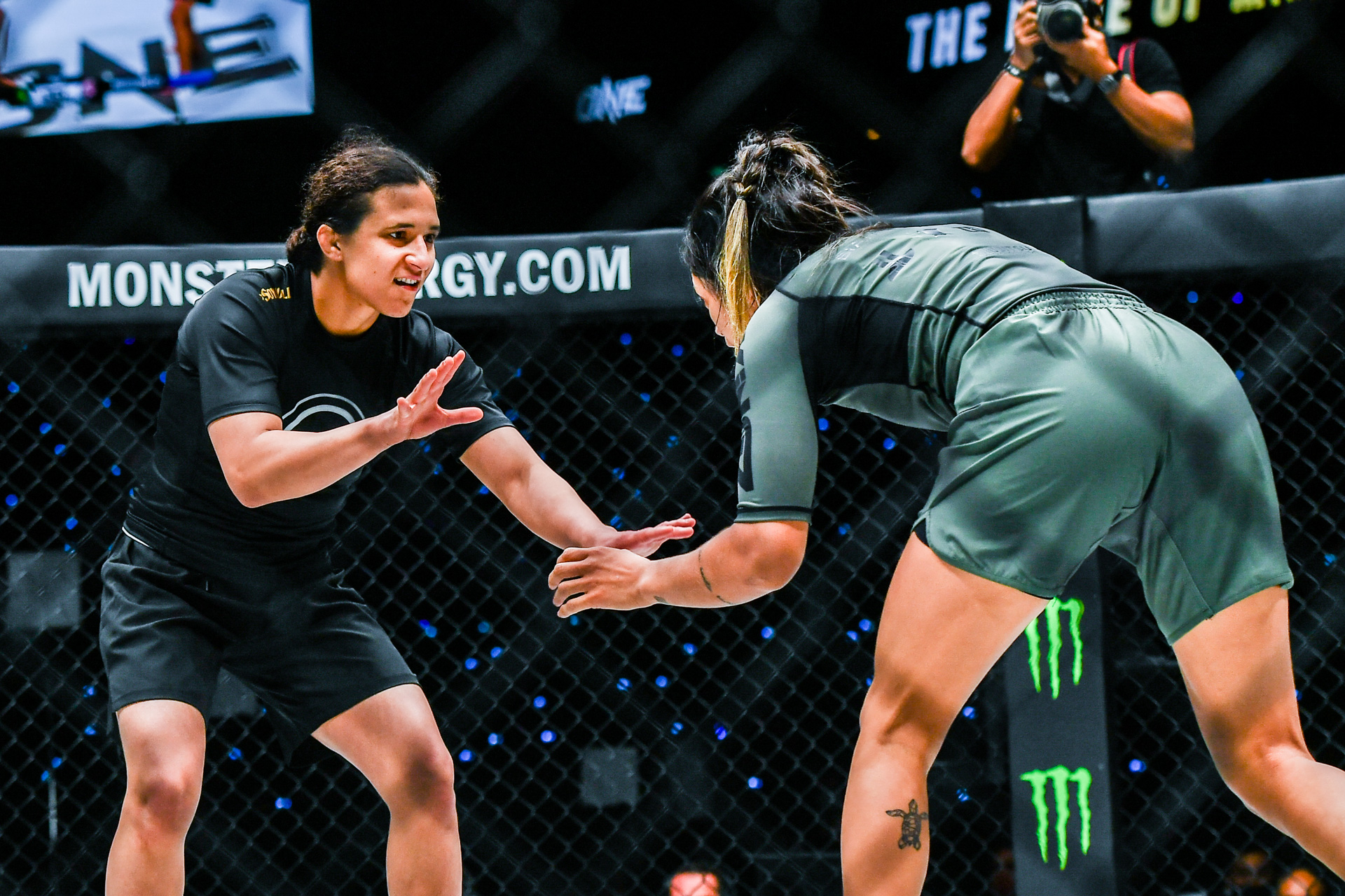 Two female no-gi grapplers competing in tight, compression-fit rashguards inside the ONE Championship cage