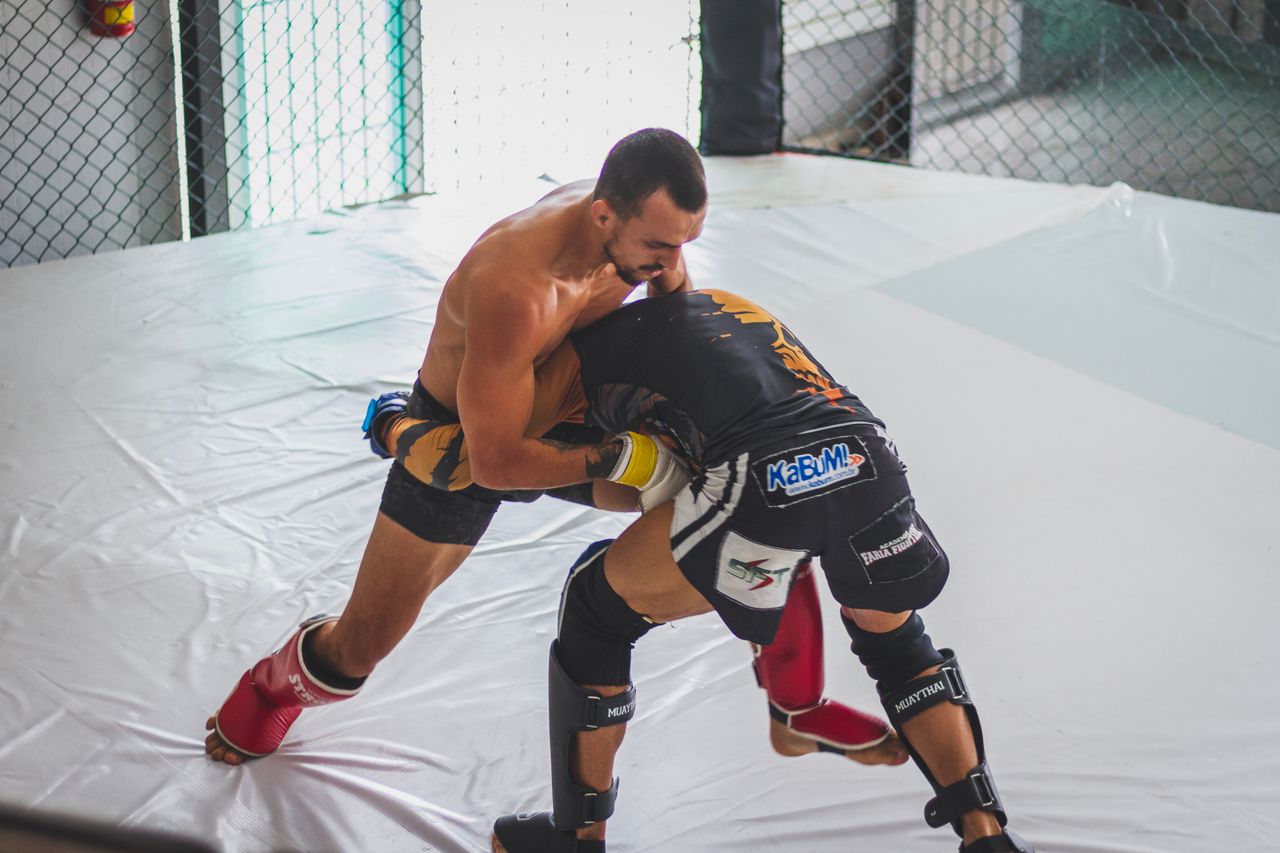 MMA fighters in cage clinch — pressure wrestling and body lock control