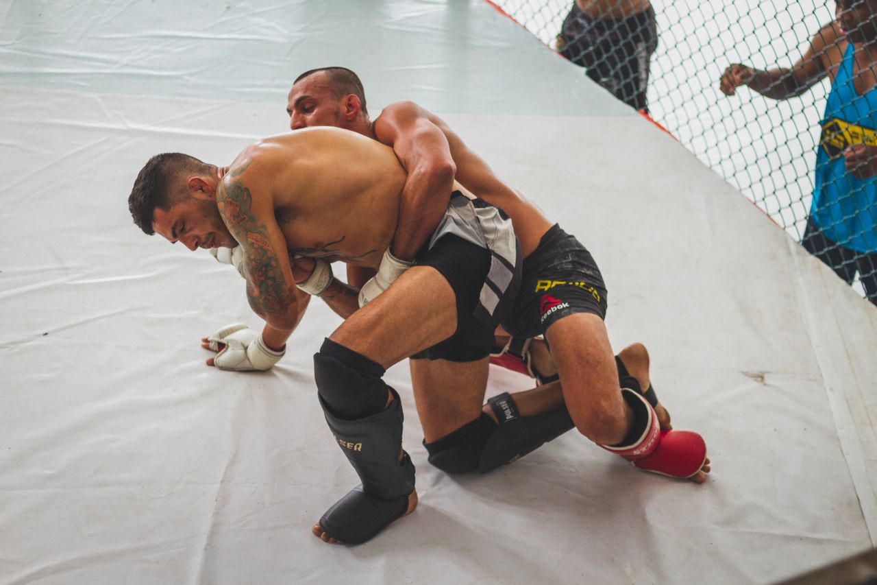 MMA fighters wrestling in the cage — takedown pressure and grappling control