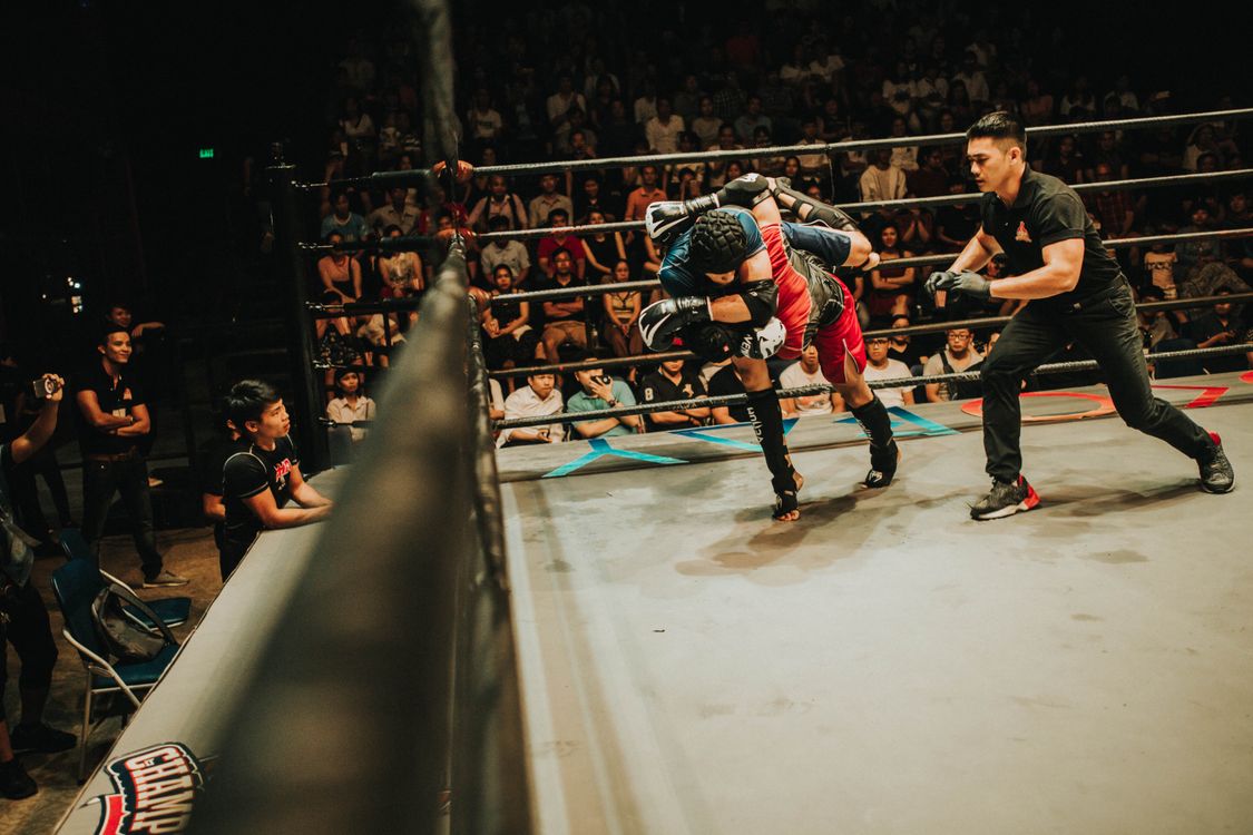 MMA fighters in a clinch with crowd watching from ringside