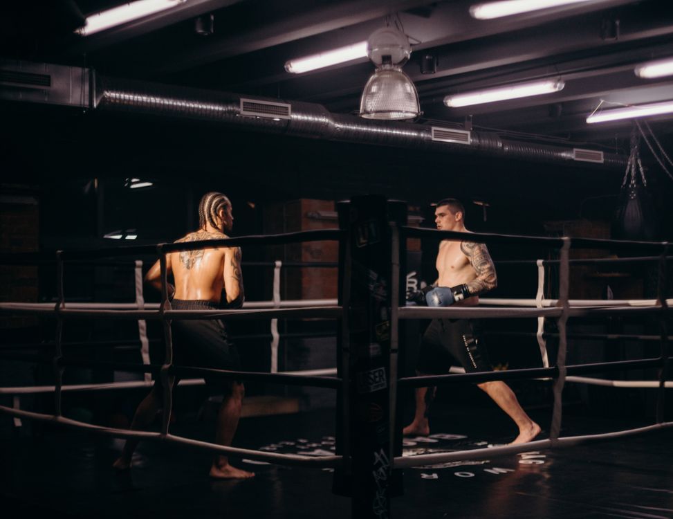 Two fighters face off in a dimly lit boxing ring